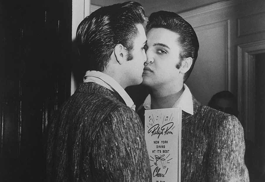 Rock star Elvis Presley pressing his nose against mirror in lobby of Warwick Hotel. (Photo by Ben Mancuso//Time Life Pictures/Getty Images)