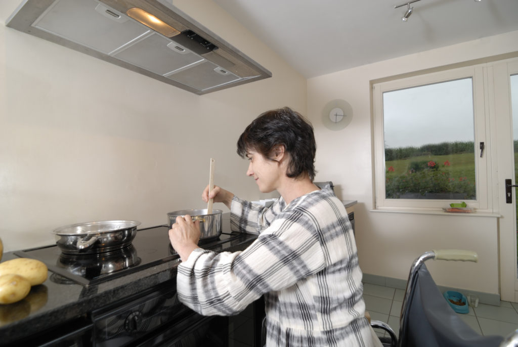 Femme handicapé en chaise roulante dans la cuisine