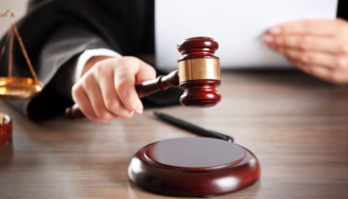 Judge,Hitting,Gavel,With,Paper,At,Wooden,Table,Closeup